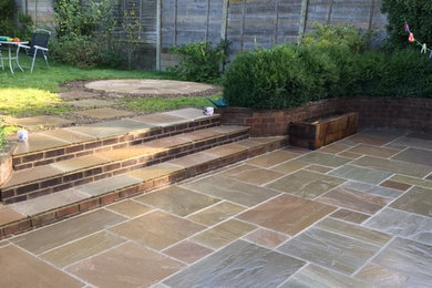 Design ideas for a medium sized classic back patio in Hertfordshire with natural stone paving.