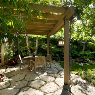 Ispirazione per un patio o portico boho chic dietro casa con fontane, pavimentazioni in cemento e una pergola