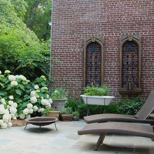 Immagine di un patio o portico eclettico dietro casa con un focolare