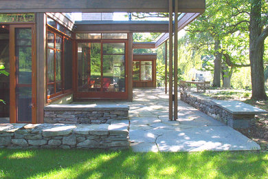 Example of a large minimalist backyard stone patio design in Boston