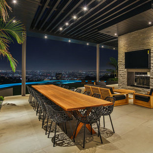 Foto di un grande patio o portico design dietro casa con lastre di cemento, un tetto a sbalzo e un caminetto