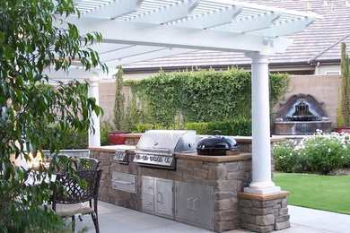 Large tuscan backyard concrete patio kitchen photo in Other with a pergola