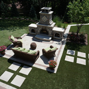 Immagine di un grande patio o portico classico dietro casa con pavimentazioni in cemento, un focolare e nessuna copertura