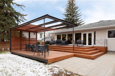 Modelo de patio moderno grande en patio trasero con entablado y pérgola