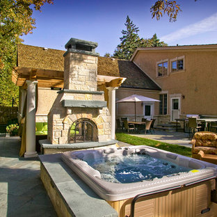 Immagine di un patio o portico eclettico dietro casa con pavimentazioni in pietra naturale, nessuna copertura e un focolare