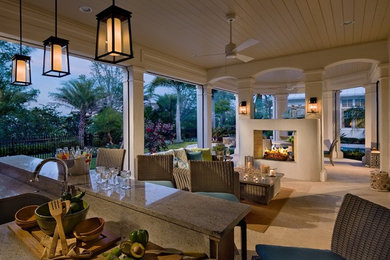 Example of a mid-sized island style backyard stone patio kitchen design in Orlando with a roof extension