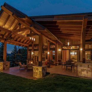 Esempio di un grande patio o portico design dietro casa con un focolare, cemento stampato e un tetto a sbalzo
