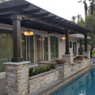 Ispirazione per un patio o portico minimalista di medie dimensioni e dietro casa con una pergola e piastrelle