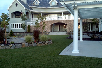 Imagen de patio actual de tamaño medio en patio trasero con losas de hormigón y pérgola