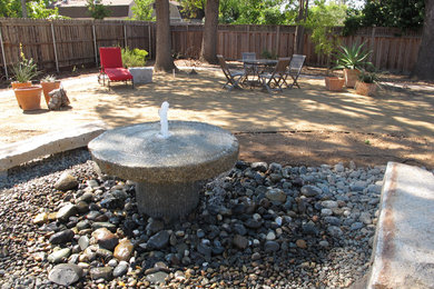 Moderner Patio hinter dem Haus mit Wasserspiel und Granitsplitt in Sacramento