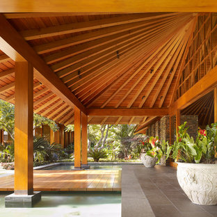 Idee per un patio o portico tropicale con un tetto a sbalzo