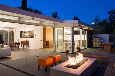 This is an example of a medium sized contemporary back patio in San Francisco with a fire feature, concrete slabs and no cover.