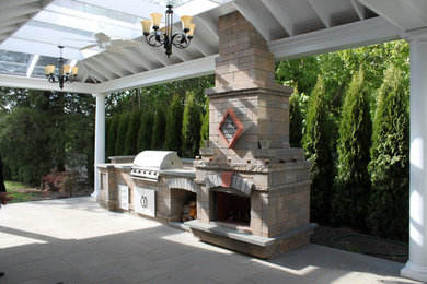 Patio kitchen - traditional backyard stone patio kitchen idea in New York with a roof extension