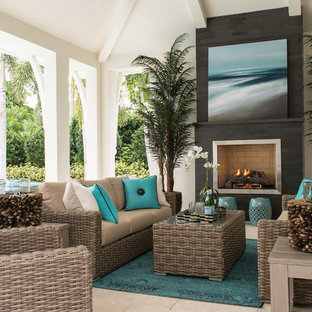 Immagine di un grande patio o portico stile marino dietro casa con piastrelle, un tetto a sbalzo e un caminetto