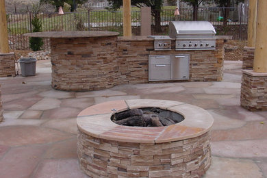 This is an example of a medium sized back patio in Albuquerque with an outdoor kitchen, natural stone paving and a pergola.