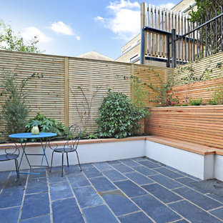Inspiration for a medium sized contemporary back patio in London with natural stone paving.