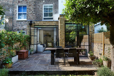 Inspiration for a scandinavian back patio in London with natural stone paving.
