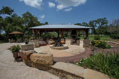 Inspiration for a large world-inspired back patio in Houston with an outdoor kitchen, natural stone paving and a gazebo.