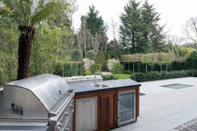 Medium sized contemporary back patio in London with natural stone paving and an outdoor kitchen.