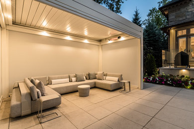 Cette image montre une petite terrasse latérale minimaliste avec des pavés en béton et une pergola.