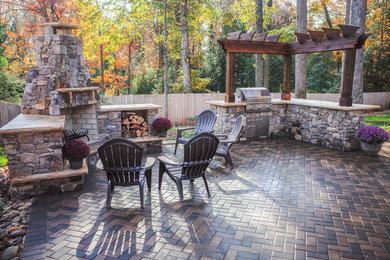 Modelo de patio de estilo americano de tamaño medio en patio trasero con cocina exterior, adoquines de ladrillo y pérgola