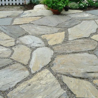 Immagine di un piccolo patio o portico country in cortile con pavimentazioni in pietra naturale