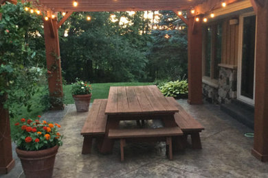 Patio - large traditional backyard patio idea in Milwaukee with a pergola