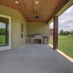 Idee per un grande patio o portico american style dietro casa con lastre di cemento e un tetto a sbalzo