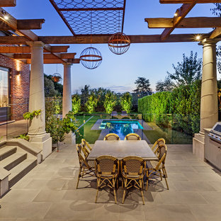 This is an example of a large transitional patio in Melbourne with an outdoor kitchen, tile and a pergola.
