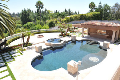 Example of a tuscan backyard stone patio kitchen design in Orange County with a gazebo