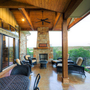 Esempio di un patio o portico american style di medie dimensioni e dietro casa con un caminetto, lastre di cemento e un parasole