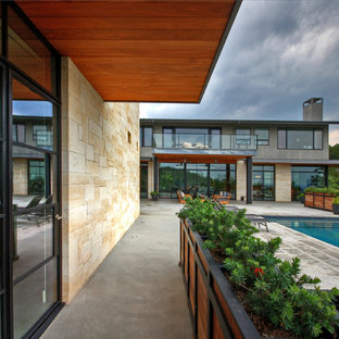 Cette image montre une terrasse design avec une extension de toiture.