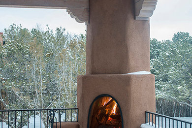 Design ideas for a large back patio in Albuquerque with a fire feature, natural stone paving and a roof extension.