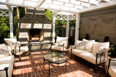 Immagine di un patio o portico classico dietro casa con un focolare, pavimentazioni in mattoni e una pergola