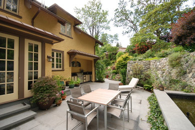 Modelo de patio clásico grande sin cubierta en patio trasero con cocina exterior y adoquines de hormigón