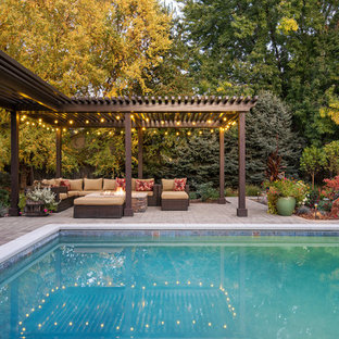 Idee per un grande patio o portico contemporaneo dietro casa con un focolare, pavimentazioni in mattoni e una pergola