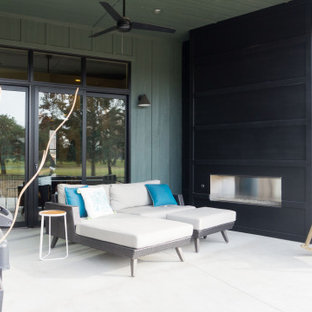 Foto di un piccolo patio o portico eclettico dietro casa con un caminetto, lastre di cemento e un tetto a sbalzo