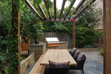 Idée de décoration pour une terrasse arrière tradition de taille moyenne avec des pavés en pierre naturelle et une pergola.