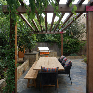 Ispirazione per un patio o portico tradizionale di medie dimensioni e dietro casa con pavimentazioni in pietra naturale e una pergola