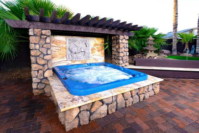 This is an example of a small world-inspired back patio in Phoenix with a water feature.