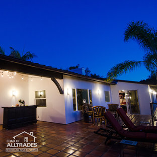 Foto di un ampio patio o portico eclettico dietro casa con piastrelle e un tetto a sbalzo
