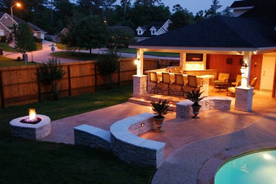 Example of a trendy backyard stamped concrete patio design in Houston with a fire pit and a roof extension