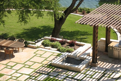 Example of a backyard stone patio fountain design in Austin with a pergola