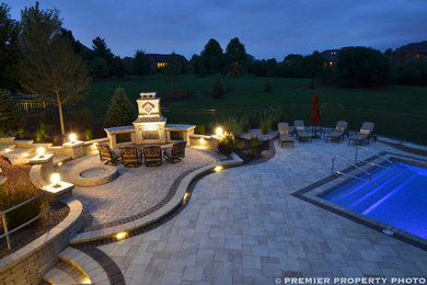 Example of a huge trendy backyard concrete paver patio design in Chicago with a fire pit and a pergola