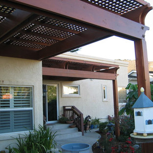 Idee per un grande patio o portico costiero dietro casa con cemento stampato e una pergola