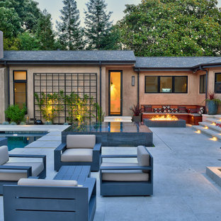 Immagine di un grande patio o portico design dietro casa con un focolare, nessuna copertura e piastrelle