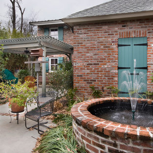 Inspiration for an expansive traditional courtyard patio in New Orleans with a water feature, concrete slab and a pergola.