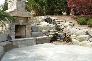 Modelo de patio rústico de tamaño medio en patio trasero con brasero y adoquines de piedra natural