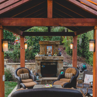Immagine di un piccolo patio o portico etnico dietro casa con un caminetto, pavimentazioni in cemento e una pergola