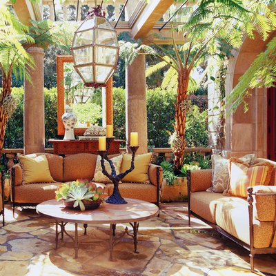 Example of a tuscan stone patio design in Orange County with a pergola